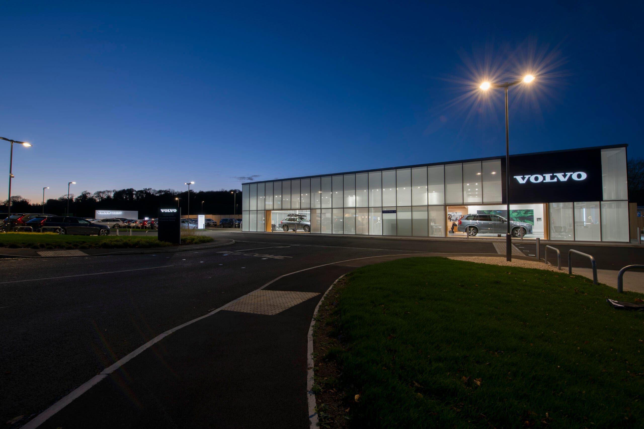 Modern Volvo dealership lit up at night.